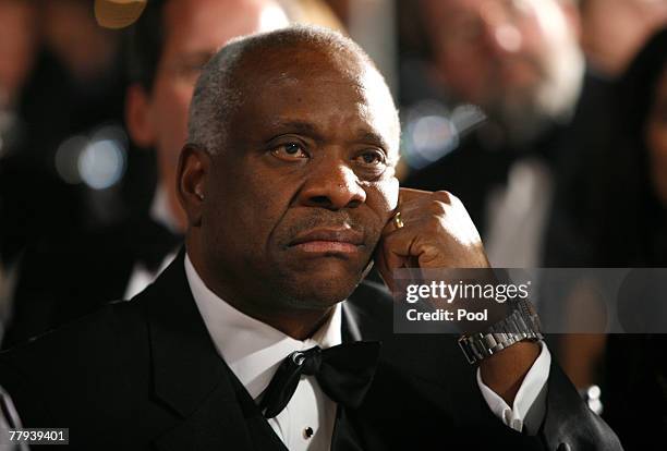 Supreme Court Justice Clarence Thomas listens to U.S. President George W. Bush speak at the the Federalist Society's 25th annual gala at the...