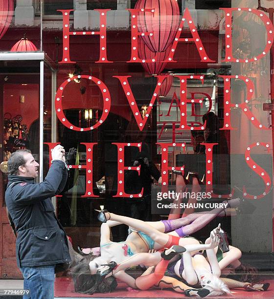Man takes pictures as he walks past an Agent Provocateur shop 16 November 2007 in a street of London. Agent Provocateur, a leading player in the...