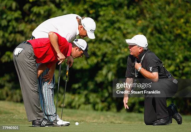 Mike Weir of Canada and playing partner Jarmo Sandelin of Sweden inspect the 12th hole with a referee after his ball jumped out of the cup and thus...