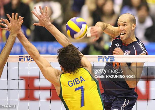 Attacker William Priddy smashes the ball past Brazilian volleyball star and captain Gilberto Godoy Filho "Giba" during a match of the men's World Cup...