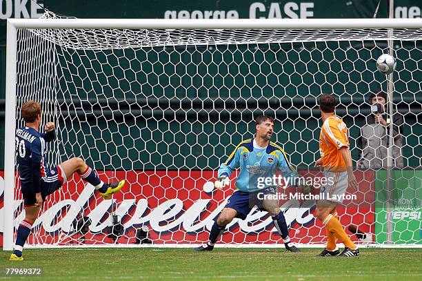 Taylor Twellman of the New England Revolution scores the first goal of the game past goalie Pat Onstad of the Houston Dynamo as Eddie Robinson looks...