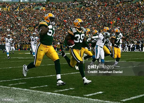 Tramon Williams of the Green Bay Packers returns a punt for a touchdown against the Carolina Panthers as teammate Jason Hunter runs with him on...