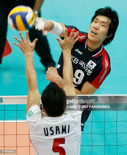 South Korean team captain Shin Young-Soo spikes the ball as Japanese Daisuke Usami blocks during the first round match of the FIVB men's World Cup...