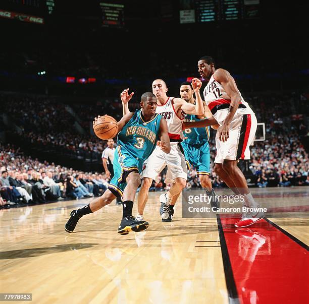 Chris Paul of the New Orleans Hornets drives the ball past Steve Blake and LaMarcus Aldridge of the Portland Trail Blazers during the game on...