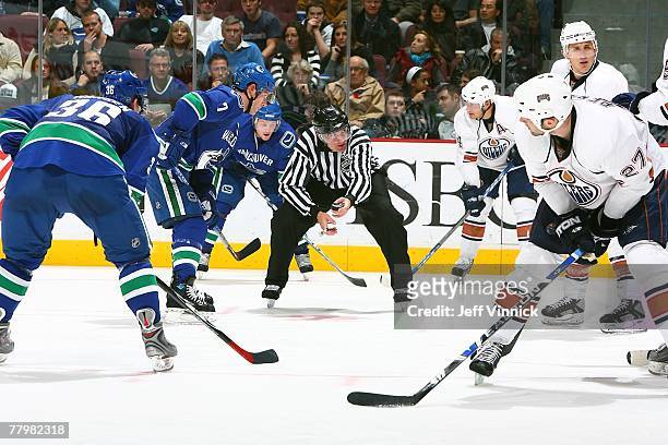 Linsmen Shane Heyer prepares to drop the puck during the game between the Vancouver Canucks and the Edmonton Oilers at General Motors Place on...