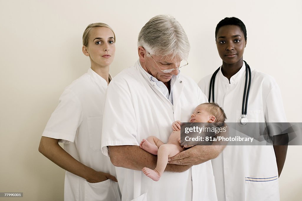 Portrait of delivery team holding a new born baby