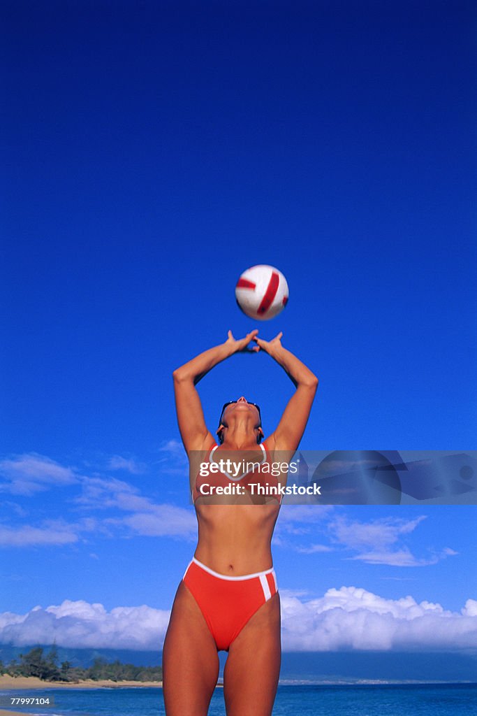 Woman on beach hitting volleyball