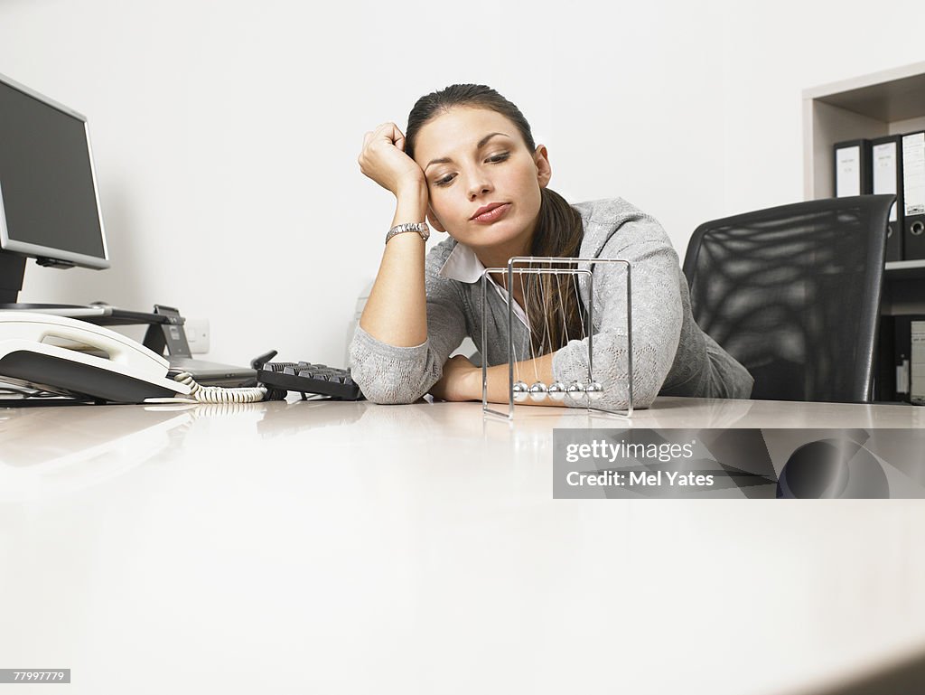 Businesswomen sitting at her desk with a Newton's Cradle