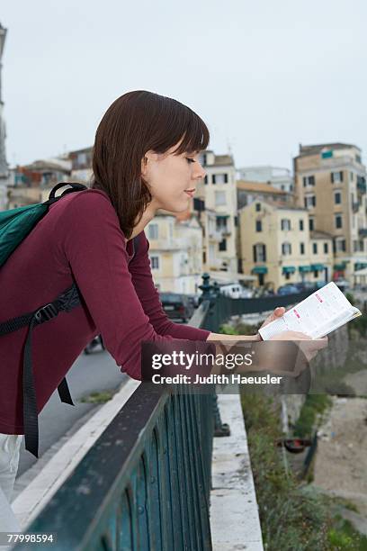 young woman with travel book reading old city in background. - old book side stock pictures, royalty-free photos & images