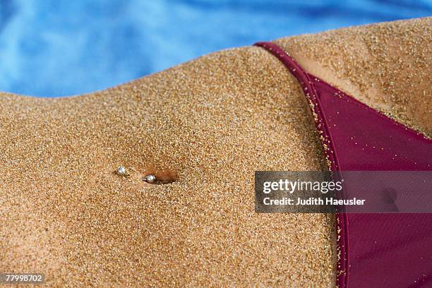 close up of sandy belly piercing in belly button bikini bottom in section. - belly button piercing foto e immagini stock