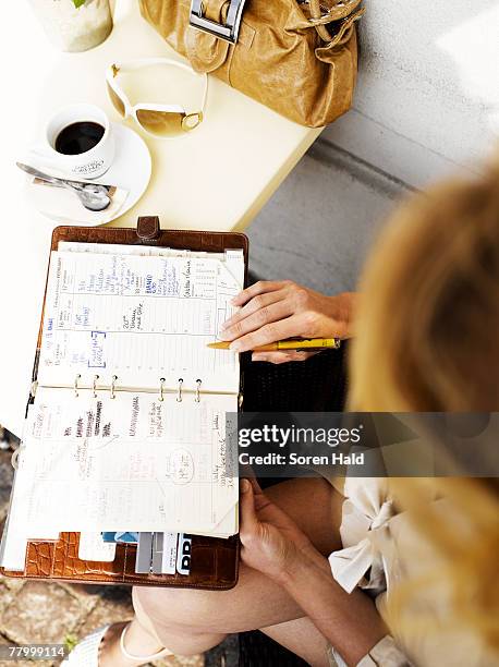 woman at an outdoor restaurant with her day planner - woman writing on calendar stock pictures, royalty-free photos & images
