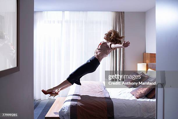 woman jumping onto bed - king size bed photos et images de collection