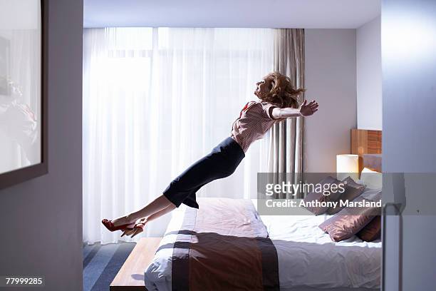 woman jumping onto bed - letto matrimoniale foto e immagini stock