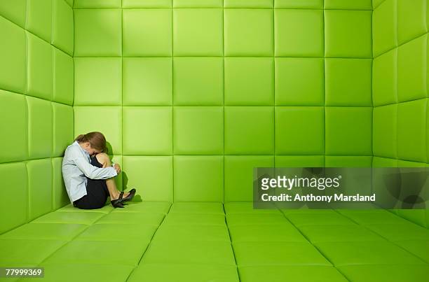 woman crouched in a corner in a green padded cell - capitonné photos et images de collection