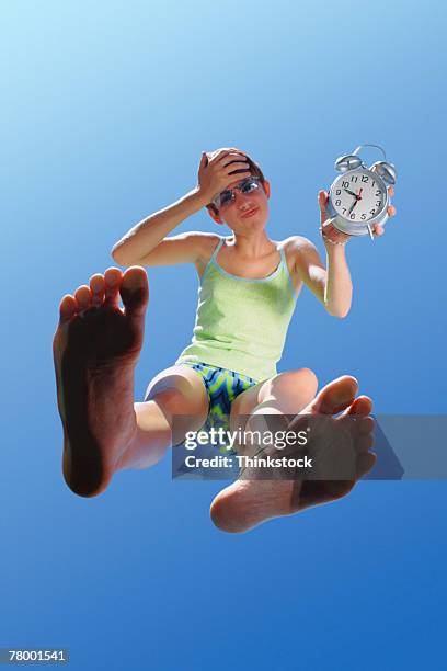teenage girl holding alarm clock - barefoot girl stock-fotos und bilder