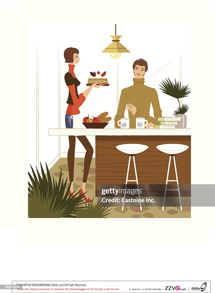 Man sitting at a table with a woman holding a cake beside him