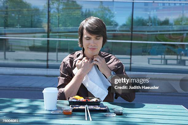 businessman eating sushi outside using napkin. - eating with a bib stock pictures, royalty-free photos & images