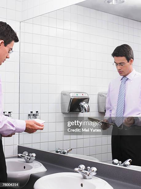 man practicing speech in office washroom mirror - office bathroom stock-fotos und bilder