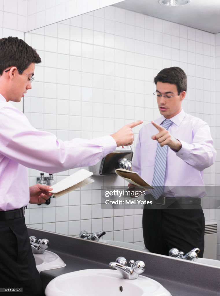 Man practicing speech in office washroom mirror