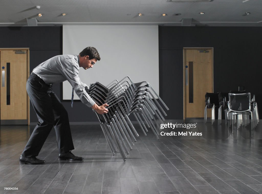 Move Stacking Man Moving Stack Of Chairs In Empty Presentation Room High-Res Stock ...