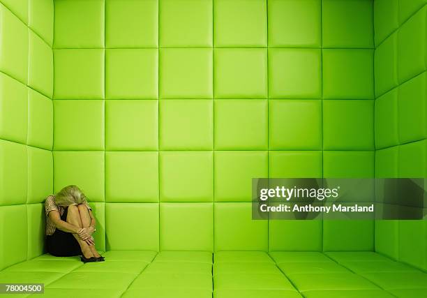 woman crouching in corner of green padded cell - capitonné photos et images de collection