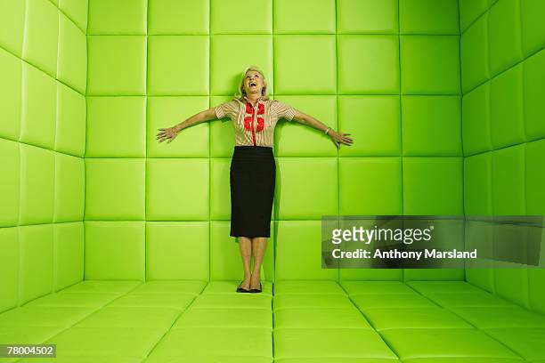 woman laughing standing against wall of green padded cell - capitonné photos et images de collection