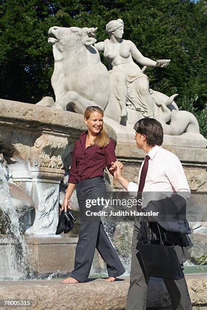 smiling couple beside fountain holding hands. - hands fountain water stock-fotos und bilder