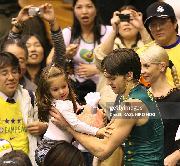 Brazilian volleyball star Gilberto Godoy Filho "Giba" holds his daughter after their match of the FIVB Men's World Cup volleyball tournament against...
