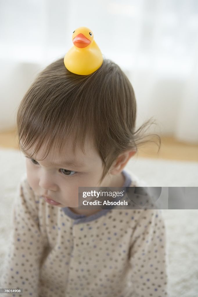 A baby with a duck toy on his head