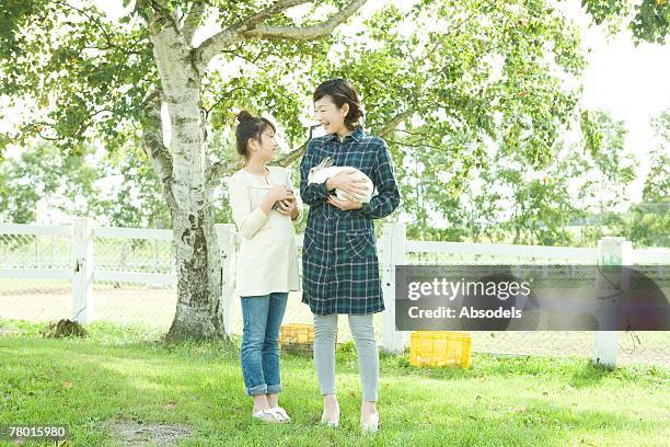 mother and daughter holding rabbit, looking at each other outside under tree - six under ストックフォトと画像