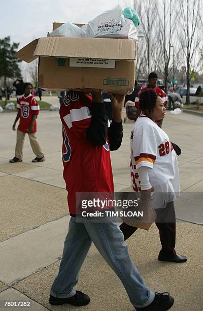 Local high school football player carries a holiday food basket for Gloria Wilson of Landover, Maryland, during an event sponsored by the NFL's...