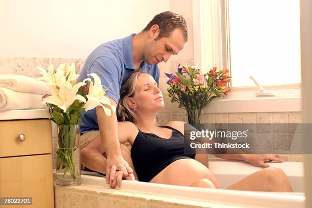 expecting couple in bathtub for water birth - bad breath stockfoto's en -beelden