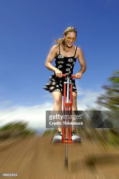 woman bouncing on pogo stick - pogo stick stock pictures, royalty-free photos & images