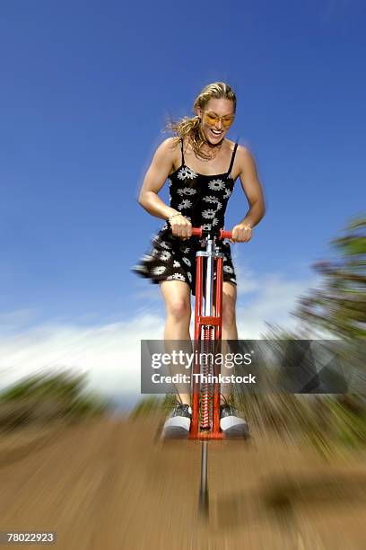 woman bouncing on pogo stick - pogo imagens e fotografias de stock