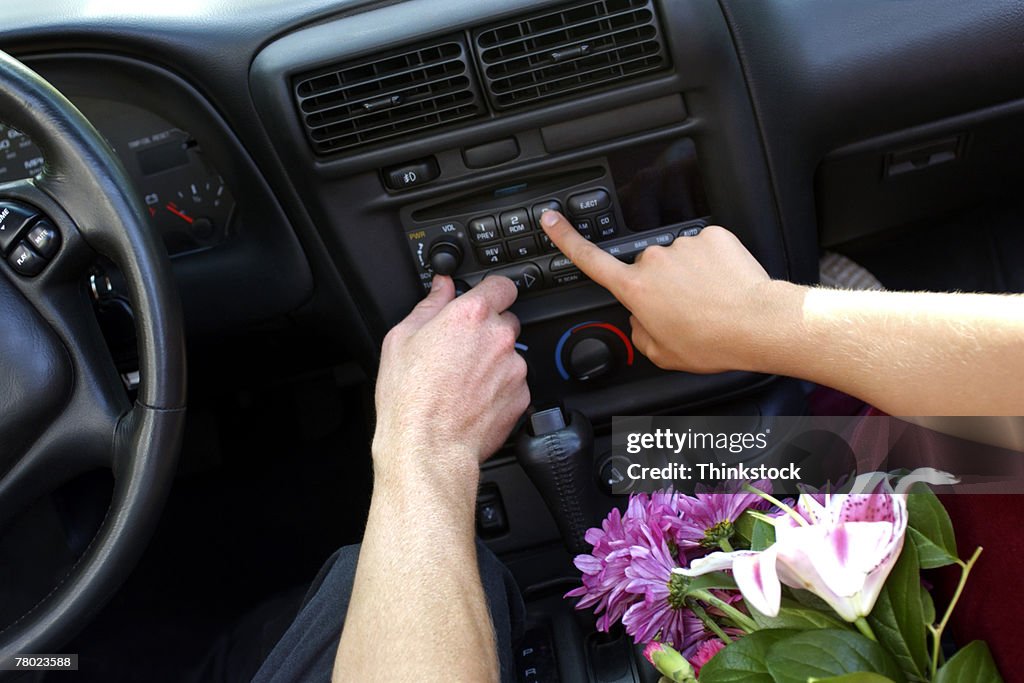 Close-up of two hands pressing buttons to adjust the car stereo.