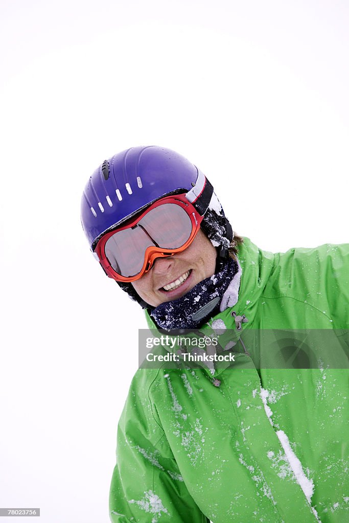 Portrait of a free skier smiling at the viewer while bundled up with a coat, toboggan and goggles