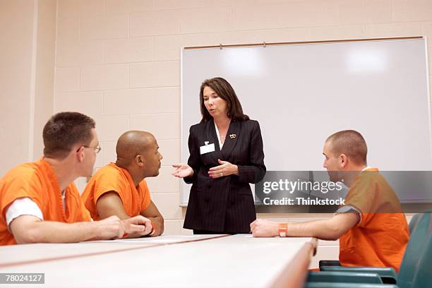 three inmates listen to a woman discuss options and privileges that they might earn while serving time in prison. - prison foto e immagini stock