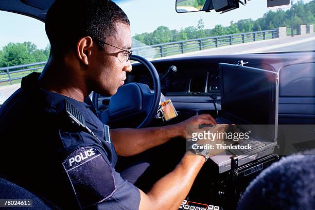 policeman working on computer in car - police stock pictures, royalty-free photos & images
