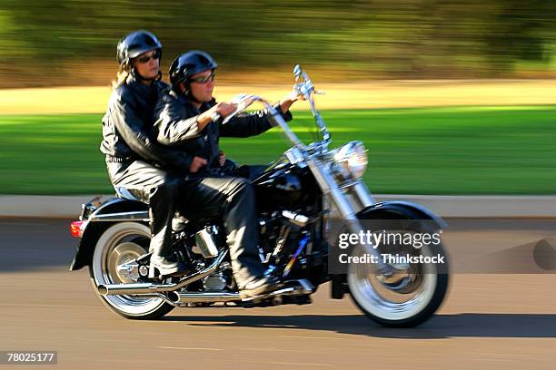 motion blurred shot of a couple riding fast past the viewer on a motorcycle. - fast motion stock pictures, royalty-free photos & images