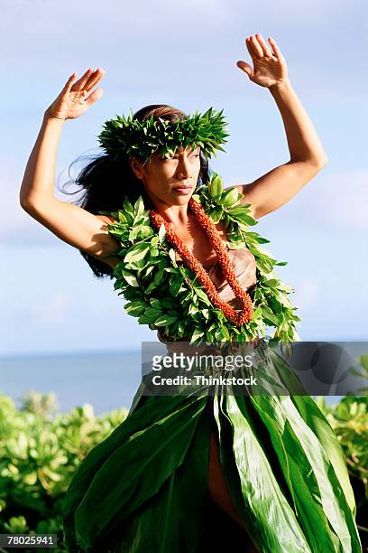 a female hula dancing outdoors near the ocean. she is wearing a traditional hawaiian skirt, lei, and matching headband.  - hula dancing stock pictures, royalty-free photos & images