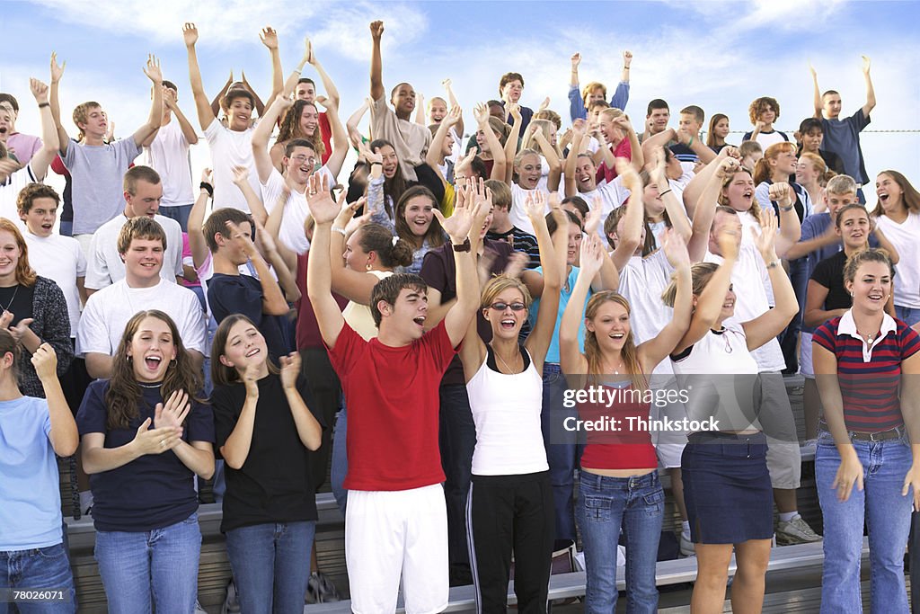 Wide shot of a crowd cheering in the stands at an outdoor event