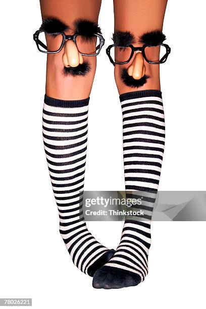 close-up of a woman's legs wearing striped knee socks and groucho marx glasses on her knees. - pigeon toed stockfoto's en -beelden