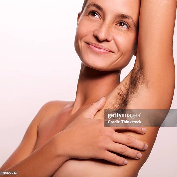 close-up of a smiling nude woman covering her breast with her hand; her armpit unshaven. - female hairy arms stock pictures, royalty-free photos & images