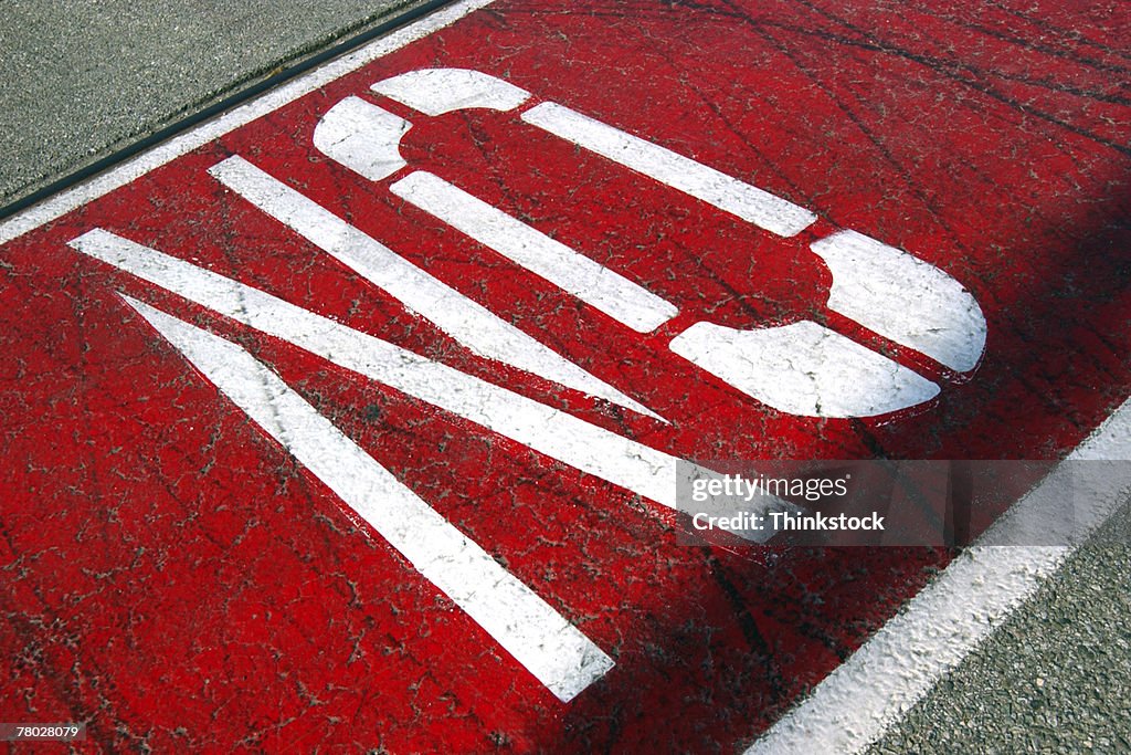 Close-up of a painted sign reading NO on pavement.