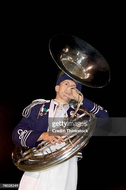 low angle of a boy playing his tuba as part of the marching band performance. - tube foto e immagini stock