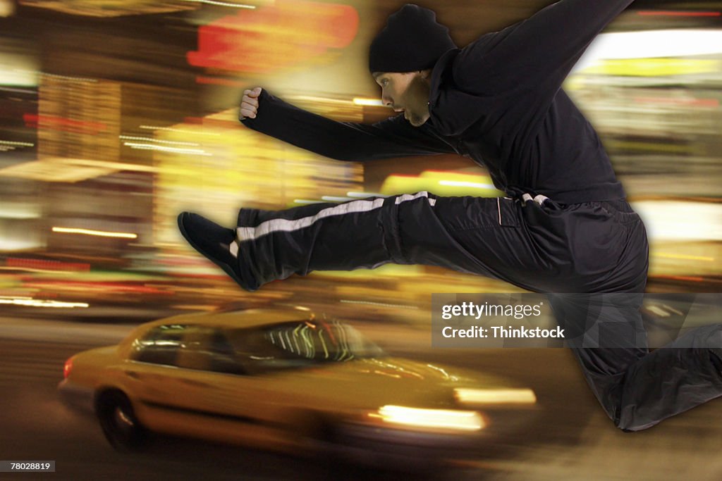 Composite image of a man leaping over a fast moving taxi cab