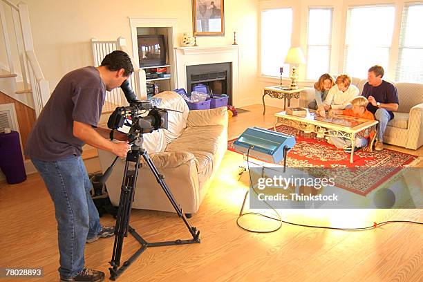 a movie production with the camera man using a tripod to videotape a family scene in a living room. - 實況電視 個照片及圖片檔