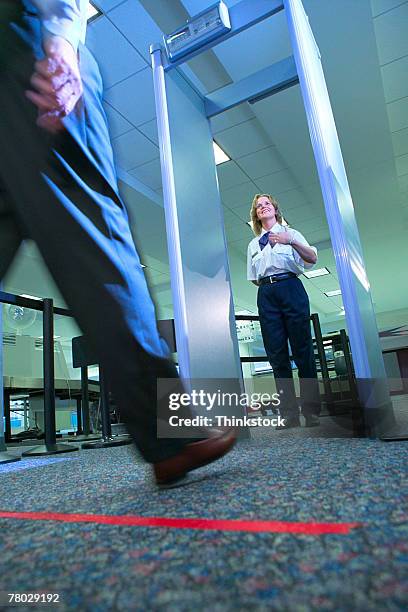 low angle close-up of a business traveler's leg as he prepares to walk through the metal detector at the airport security checkpoint - security scanner stock pictures, royalty-free photos & images