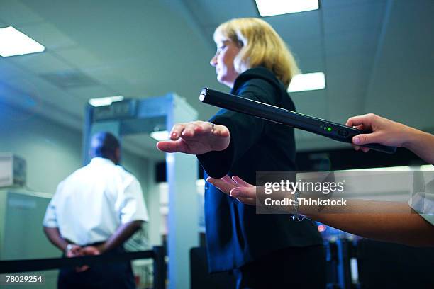 close-up of an airport security officer using a hand held metal detector to check a traveler - security scanner stock pictures, royalty-free photos & images