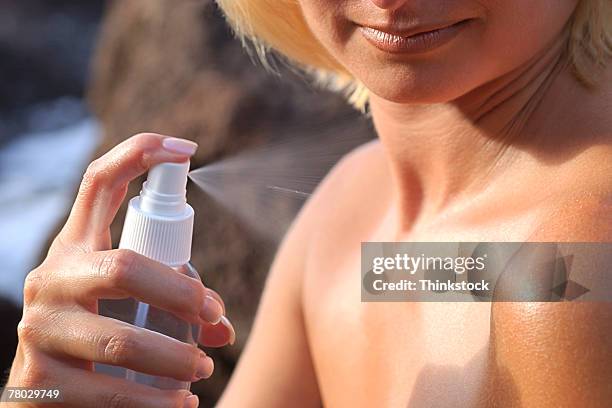 close-up of a woman spraying mist on her shoulder and chest - fly spray stock pictures, royalty-free photos & images